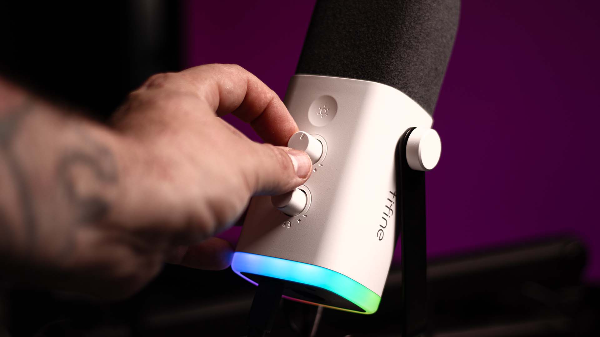 A hand adjusting the volume dials on white Fifine AM8 microphone